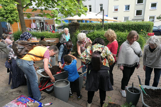 Gruppe von Erwachsenen und Kindern mit einer Schubkarre